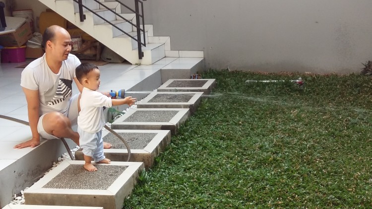 13 months old - watering the garden. He still loves doing this each morning and afternoon. gross motor skill, baby milestone, walking, montessori inspire, montessori, indonesia montessori, watering the garden, menyiram tanaman, mainan anak